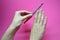 Closeup of hands of a young woman filing her nails with pink nail file