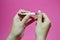 Closeup of hands of a young woman filing her nails with pink nail file