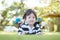 Closeup happy asian kid lied on grass floor in the garden background with cute motion