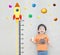 Closeup happy asian kid stand for measure height with cute cartoon at the marble stone wall textured background in growth of kid c