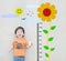 Closeup happy asian kid stand for measure height with cute cartoon sunflower at the marble stone wall textured background