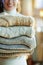 Closeup on happy young woman holding pile of sweaters