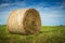 Closeup of a haystack in a grass field with blue sky