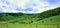 Closeup of haystack rolls in the green field, green hilly terrain in the background