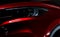 Closeup headlight of shiny red luxury SUV compact car. Elegant electric car technology and business concept. Hybrid auto