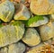Closeup of a heap of rocks covered in green mold and autumn leaves. Stone boulders surrounded by dried fallen orange and