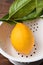 Closeup high angle shot of a single lemon with stem and leaves attached in a white colander