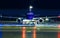 Closeup high detailed view on modern blue twin-engine passenger airplane taxiing at night by towing truck at