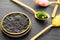 Closeup on high quality real black sturgeon caviar in a golden tin can aside golden spoons with pickles and herbs on a slate