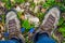 Closeup hiker feet stay on forest glade with flowers