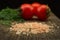 Closeup Himalayan pink coarse salt with spices on a black oak board. Tomatoes and dill on the background.