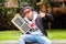 Closeup of a Hispanic DJ with a hat showing a finger-drumming musical instrument sitting outdoors