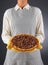 Closeup of a homemaker in an apron and oven mitts holding a fresh baked holiday Pecan Pie