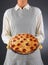 Closeup of a homemaker in an apron and oven mitts holding fresh homemade pizza. Woman is unrecognizable