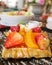 Closeup of honey waffle with strawberry and peach and icing sprinkle on black plate