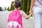 Closeup horizontal rear view of mother and little girl preschooler eith backpack go hand in hand to the kindergarten. Mom and her