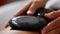 Closeup of a hot stone being used to apply gentle pressure on a persons muscles promoting deep tissue relaxation.