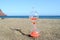 Closeup of an hourglass with reddish sand on the beach against the background of the sea and sky.