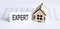 Closeup of house wooden model with blank for text EXPERT on chart background