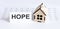 Closeup of house wooden model with blank for text HOPE on chart background