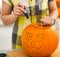 Closeup on housewife carving a big orange pumpkin Jack-O-Lantern
