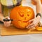 Closeup on housewife carving a big orange pumpkin Jack-O-Lantern