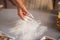 Closeup on housewife sprinkling flour on table