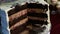 Closeup human hand make thin slice of big chocolate cake