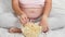 Closeup of hungry pregnant woman in pajamas sitting on bed and eating popcorn