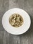 Closeup image of a bowl of cappelletti pasta against a wooden background