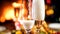 Closeup image of champagne flowing in glasses on romantic dinner at fireplace