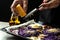 Closeup image of a chef cooking autumn dish of red cabbage baked with nuts, quince and apples, flying grated cheese scattering in