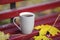 Closeup image of coffee cup in colorful maple leaves on wooden b