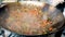 Closeup image of cook stirring vegetables frying in wok pan at outdoor kitchen