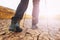 Closeup image of hiker legs in a touristic boots wallking forward on the dry cracked ground