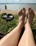 Closeup image of legs senior sitting relaxed on sandy beach.