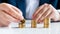 Closeup image of male banker putting golden coins in high stacks on office desk