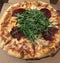 Closeup image of a pizza topped with rocket and bresaola