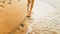 Closeup image of sexy barefoot female feet walking on the wet sand and calm warm waves at sea beach