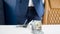 Closeup image of stack of money lying on office desk in front of businessman in blue suit