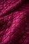A closeup image of a striking magenta quilted fabric with its beautiful diamond pattern sching. Trendy color of 2023