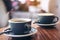 Closeup image of two blue cups of hot latte coffee and Americano coffee on vintage wooden table