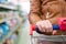 Closeup image on woman hand in a supermarket holding trolley carries with shopping shelves on the background