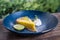 Closeup image of a yellow lemon curd cake in blue ceramic plate on wooden table