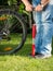 Closeup image of young man pumping flat bicycle wheel at park