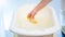 Closeup image of young mother checking water temperature in baby bathtub with thermometer