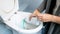 Closeup image of young woman pouring antibacterial detergent in toilet