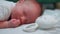 Closeup indoor shot of beautiful infant caucasian baby boy lying on his belly next to white, bunny-shaped rattle