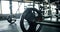 Closeup of iron heavy barbell on floor at empty gym with modern interior