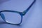 Closeup of isolated blue eyeglass lens with earpiece hinge on blank background
